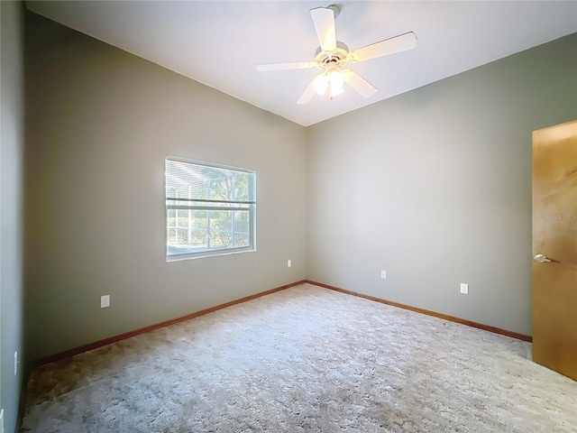 carpeted spare room with baseboards, a ceiling fan, and vaulted ceiling