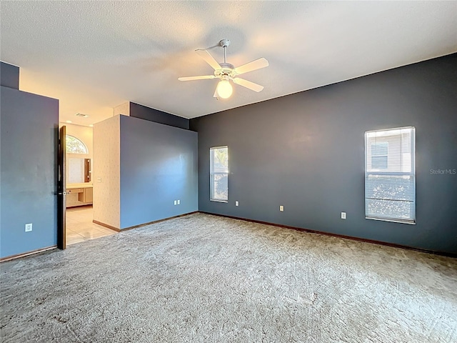 carpeted empty room featuring a ceiling fan, baseboards, a wealth of natural light, and a textured ceiling