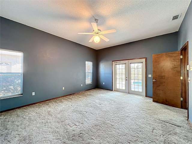 unfurnished room with visible vents, ceiling fan, carpet, french doors, and a textured ceiling