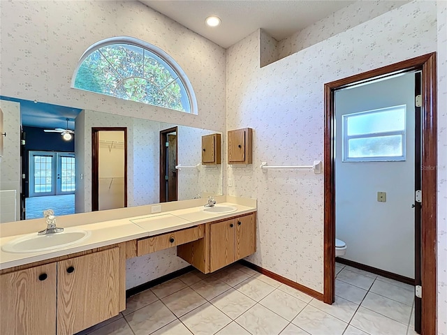 bathroom featuring a sink, plenty of natural light, and wallpapered walls