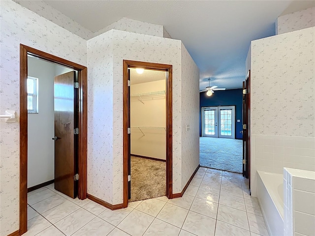 corridor featuring light tile patterned floors, french doors, light colored carpet, and wallpapered walls