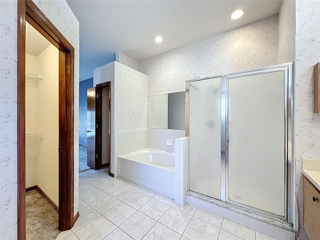 bathroom featuring a shower stall, wallpapered walls, a walk in closet, a garden tub, and tile patterned floors