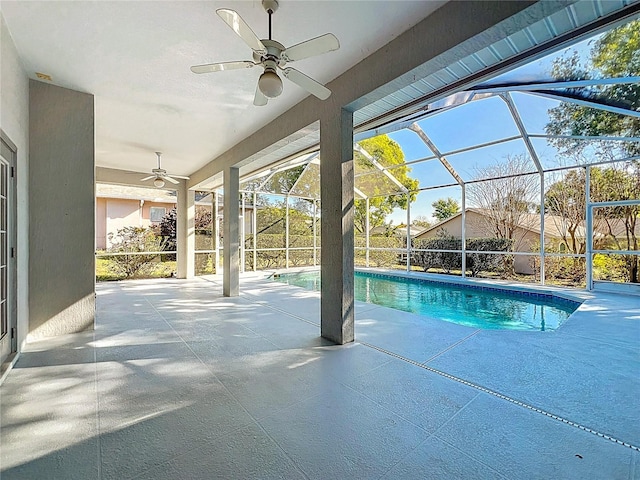 outdoor pool with glass enclosure, a patio, and ceiling fan