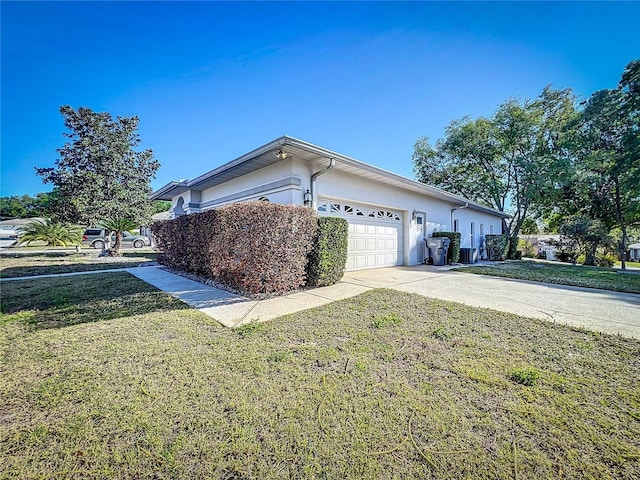 view of property exterior with an attached garage, a yard, driveway, and stucco siding