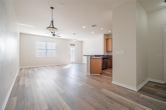 unfurnished living room with visible vents, light wood-style flooring, a textured ceiling, and baseboards