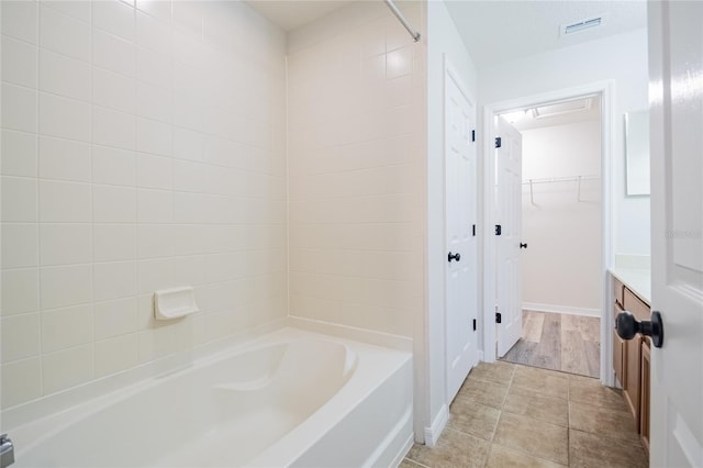 full bathroom featuring visible vents, a tub, a walk in closet, vanity, and a shower