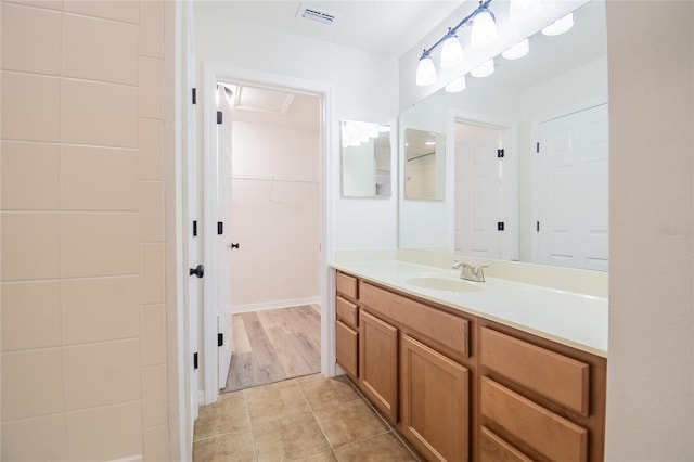 bathroom with a spacious closet, visible vents, tile patterned flooring, and vanity