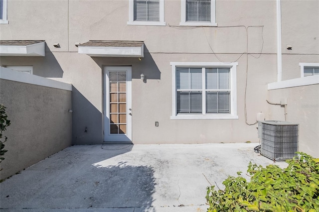 doorway to property with a patio area, central AC, and stucco siding