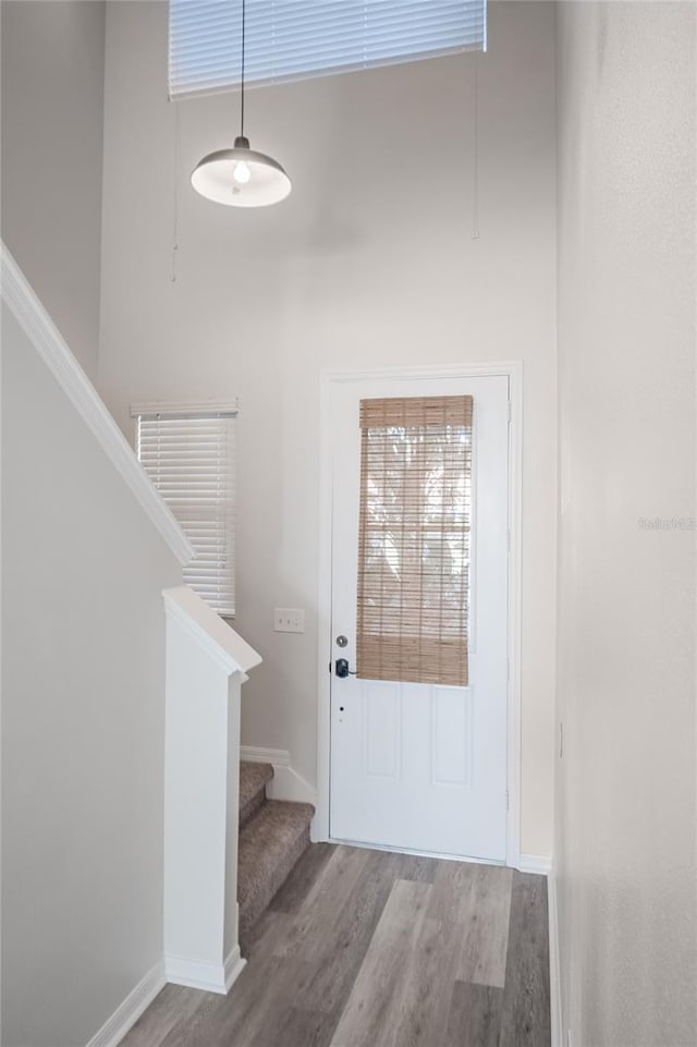 entryway with stairs, baseboards, and wood finished floors