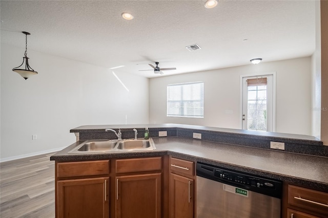 kitchen with dark countertops, a sink, visible vents, and stainless steel dishwasher