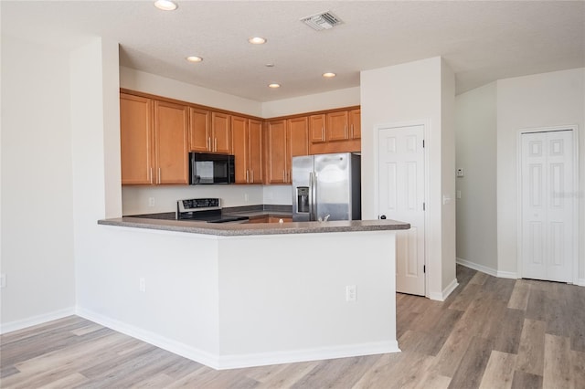 kitchen featuring visible vents, light wood-style flooring, a peninsula, appliances with stainless steel finishes, and baseboards