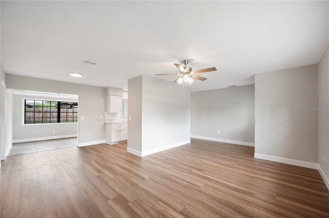 unfurnished living room featuring visible vents, baseboards, ceiling fan, and light wood finished floors