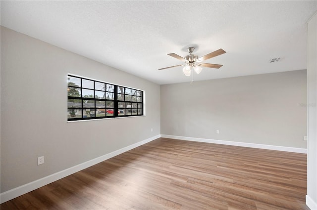 empty room with wood finished floors, baseboards, and ceiling fan