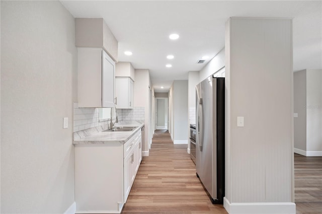 kitchen featuring light wood-type flooring, tasteful backsplash, light countertops, and freestanding refrigerator