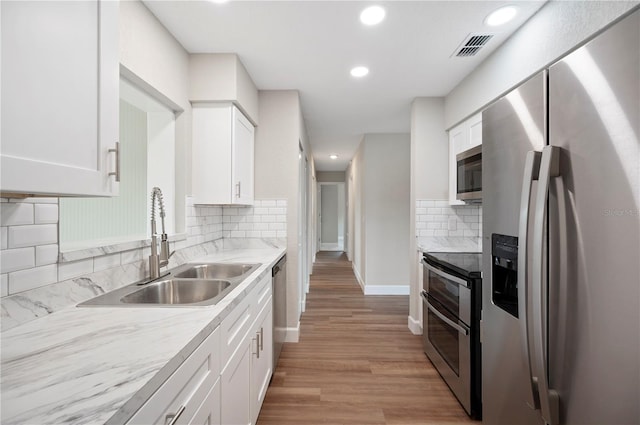 kitchen featuring white cabinets, appliances with stainless steel finishes, light countertops, and a sink