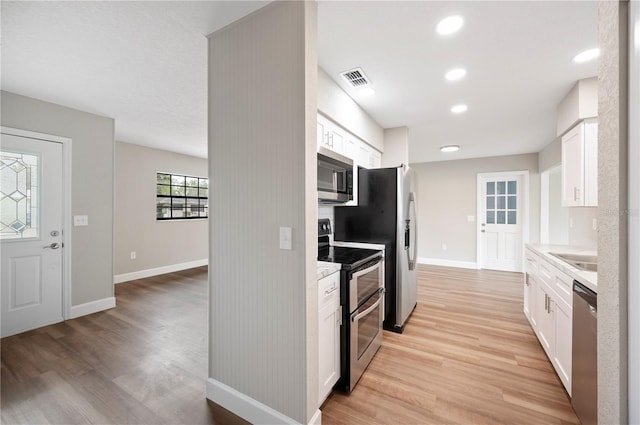 kitchen featuring stainless steel appliances, light countertops, and white cabinetry