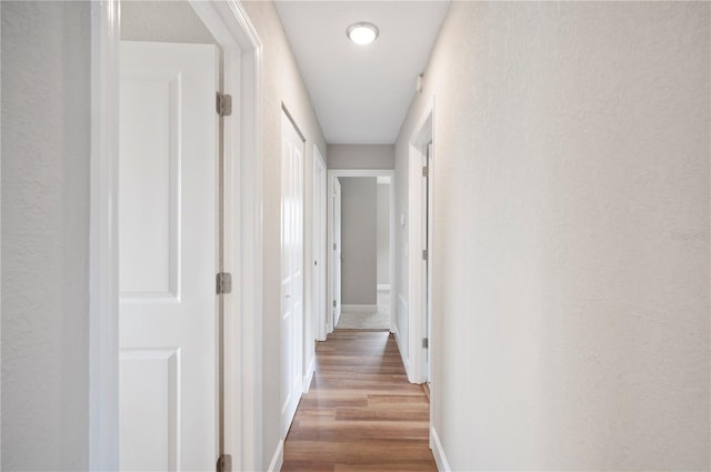 hallway featuring baseboards and wood finished floors