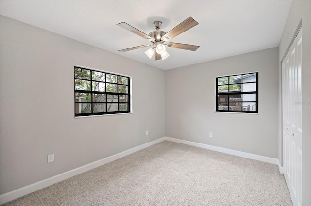 carpeted spare room featuring plenty of natural light, a ceiling fan, and baseboards