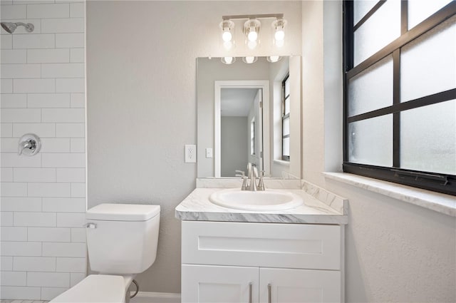 full bathroom with vanity, toilet, a wealth of natural light, and tiled shower