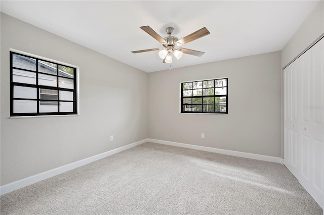 unfurnished bedroom featuring baseboards, a closet, carpet floors, and ceiling fan