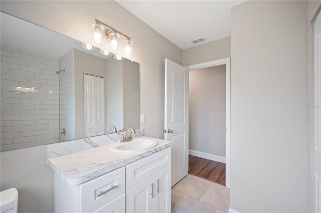 full bath featuring visible vents, baseboards, toilet, a tile shower, and vanity