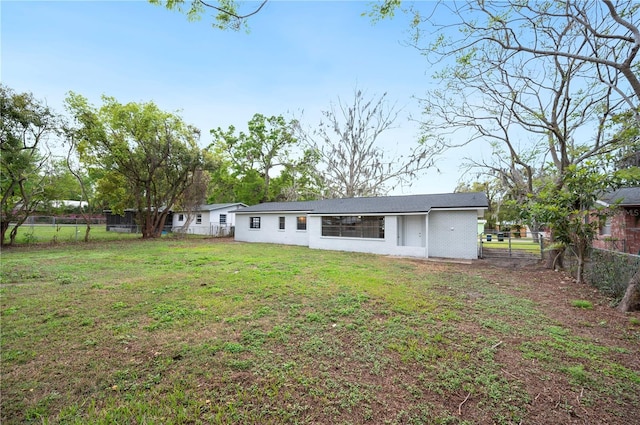 rear view of property with a lawn and fence