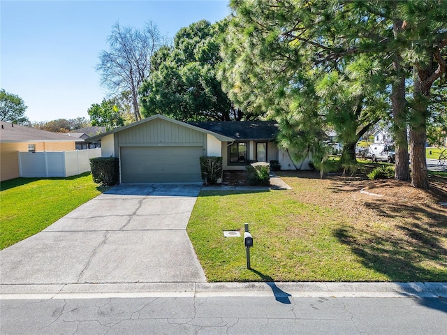 ranch-style home with a front yard, concrete driveway, fence, and an attached garage