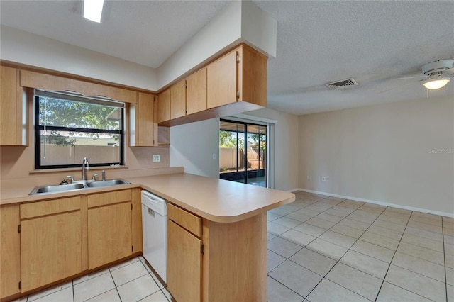 kitchen with visible vents, light countertops, a peninsula, white dishwasher, and a sink