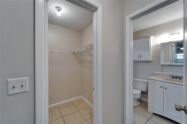 bathroom featuring a textured ceiling, toilet, vanity, and tile patterned flooring