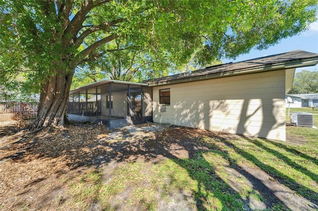 view of front facade featuring fence, central AC, and a sunroom