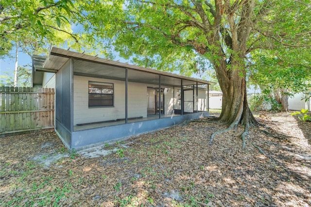 rear view of house featuring fence and a sunroom