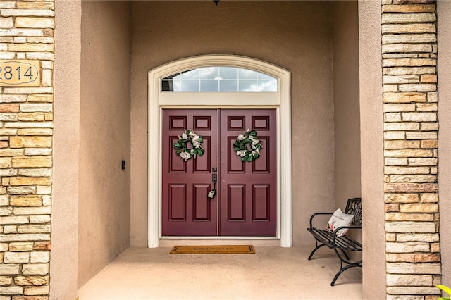 property entrance with stone siding and stucco siding