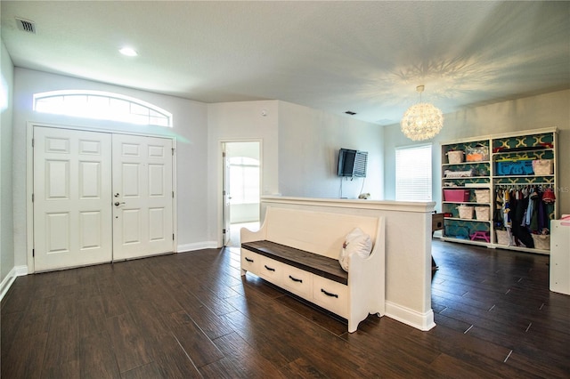 entryway with dark wood-style floors, visible vents, a healthy amount of sunlight, and a notable chandelier