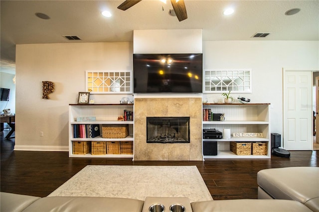 living room with ceiling fan, visible vents, wood finished floors, and a fireplace