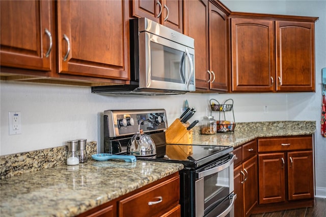 kitchen featuring light stone counters, dark wood-style floors, and appliances with stainless steel finishes