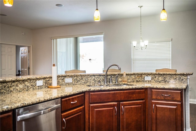 kitchen with a sink, decorative light fixtures, light stone countertops, and stainless steel dishwasher