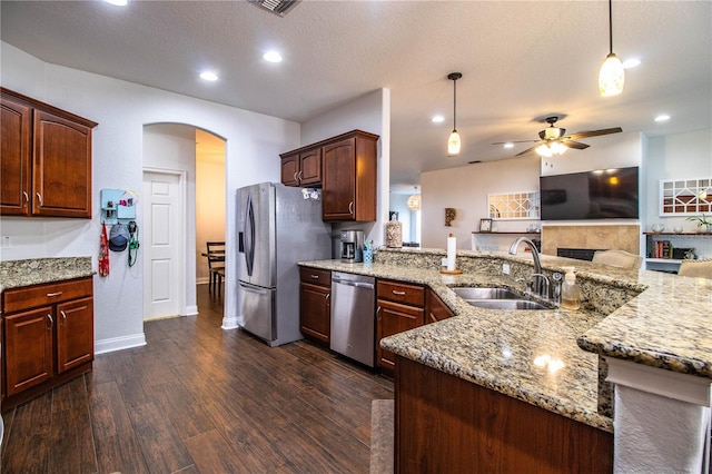 kitchen with arched walkways, stainless steel appliances, light stone counters, and a sink