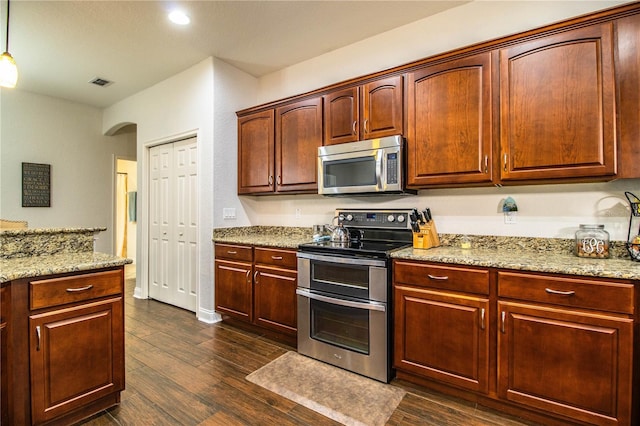 kitchen with light stone counters, dark wood-style floors, arched walkways, and appliances with stainless steel finishes