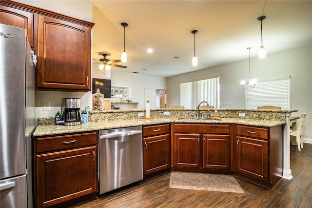 kitchen with appliances with stainless steel finishes, pendant lighting, wood tiled floor, and a sink