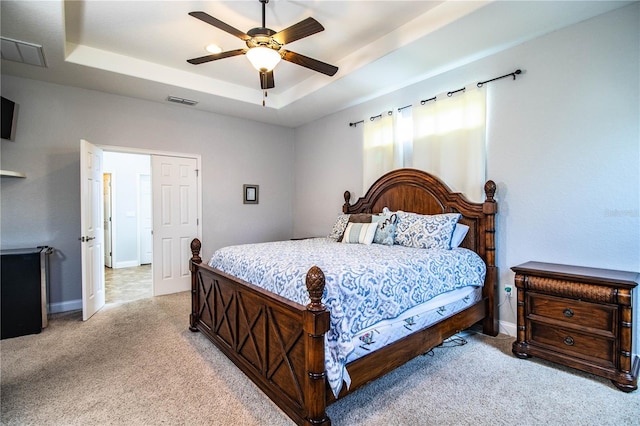 bedroom featuring baseboards, visible vents, carpet floors, a tray ceiling, and ceiling fan