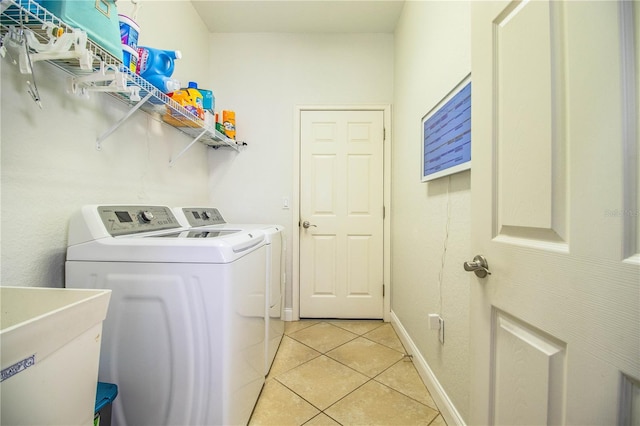 clothes washing area featuring washer and dryer, a sink, light tile patterned floors, baseboards, and laundry area