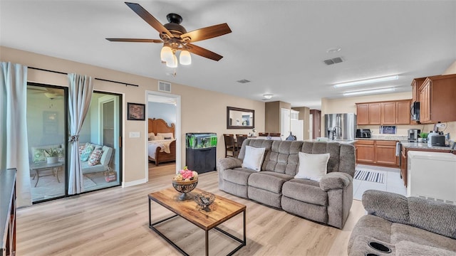 living room with light wood finished floors, visible vents, and a ceiling fan