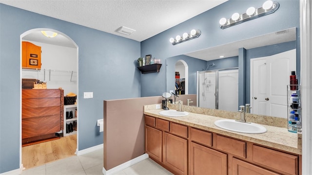 full bathroom featuring tile patterned flooring, double vanity, a textured ceiling, and a sink