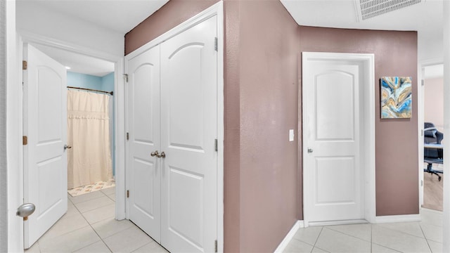 hallway featuring light tile patterned flooring, baseboards, and visible vents