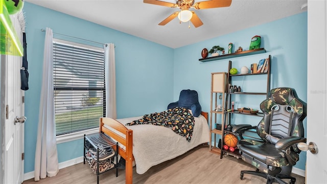 bedroom with a ceiling fan, wood finished floors, and baseboards