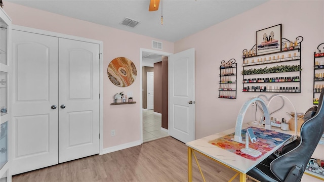 home office featuring visible vents, baseboards, light wood-style flooring, and a ceiling fan