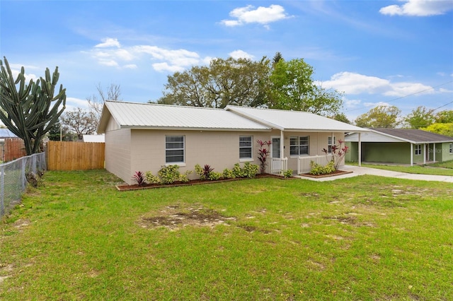 ranch-style home featuring metal roof, concrete driveway, a front lawn, and fence