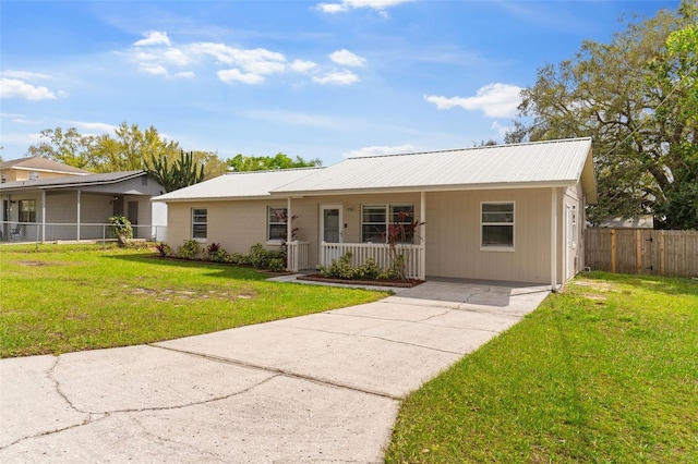 ranch-style home with fence, a porch, a front yard, metal roof, and driveway