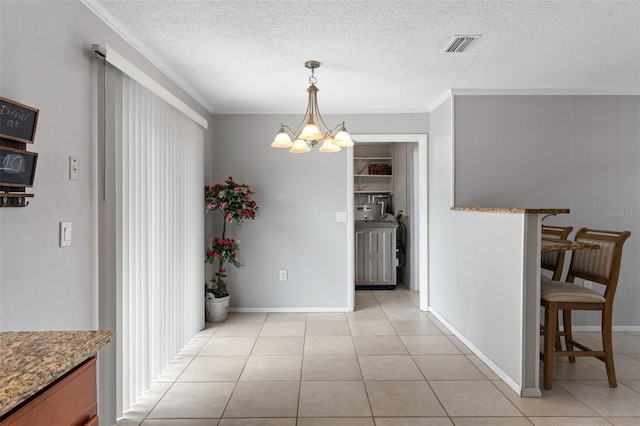 dining space featuring visible vents, a notable chandelier, a textured ceiling, crown molding, and light tile patterned floors