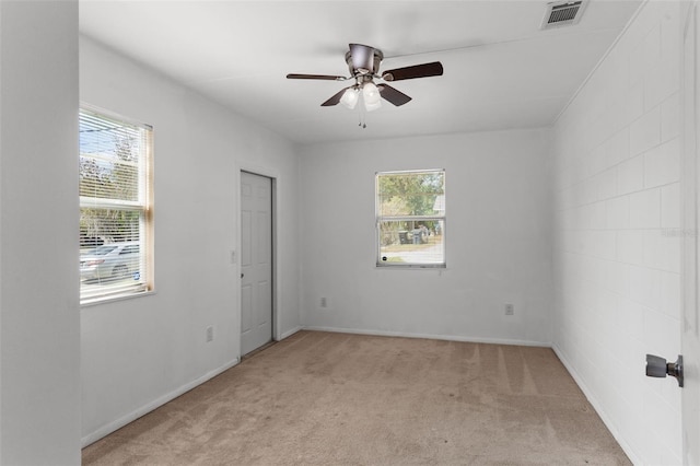 spare room with visible vents, light colored carpet, and a ceiling fan